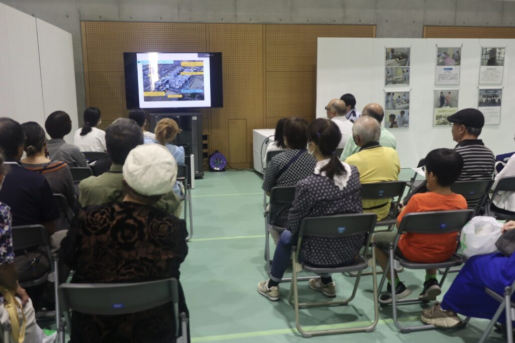 昭島矯正展で映像を見る一般来場者たち