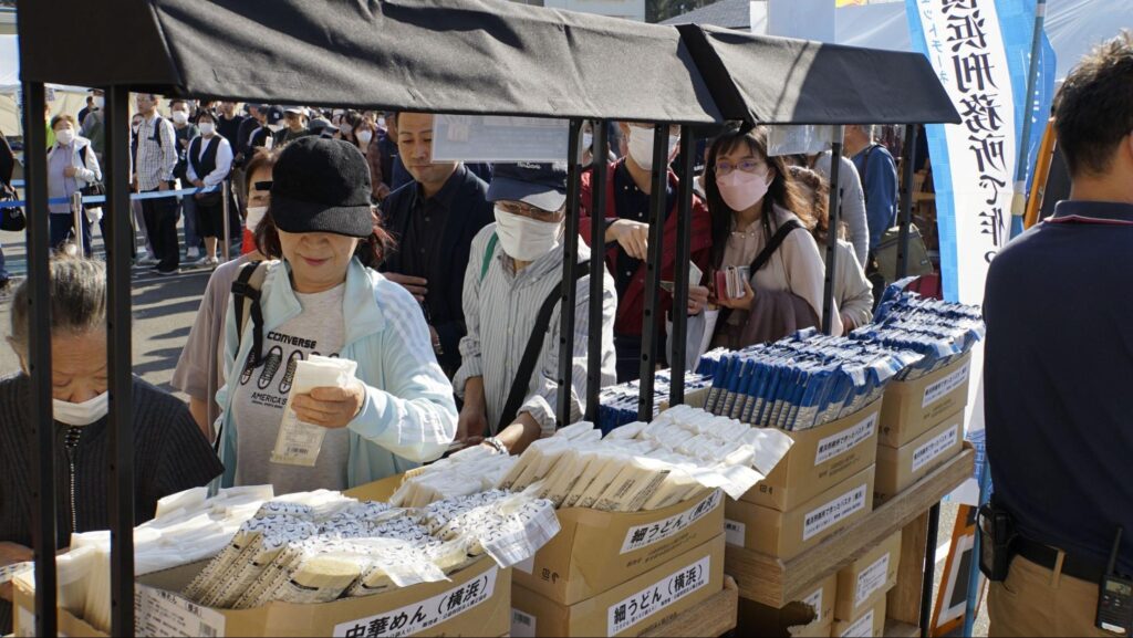 第51回横浜矯正展（2023年11月4日(土)@横浜刑務所）で販売されている「中華麺」や「細うどん」を購入する来場者たち