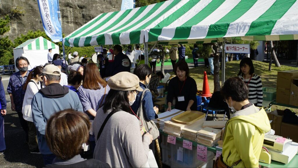 横須賀矯正展に出展された刑務所作業製品の値下げ品コーナーのブースで製品を見ている来場者たち