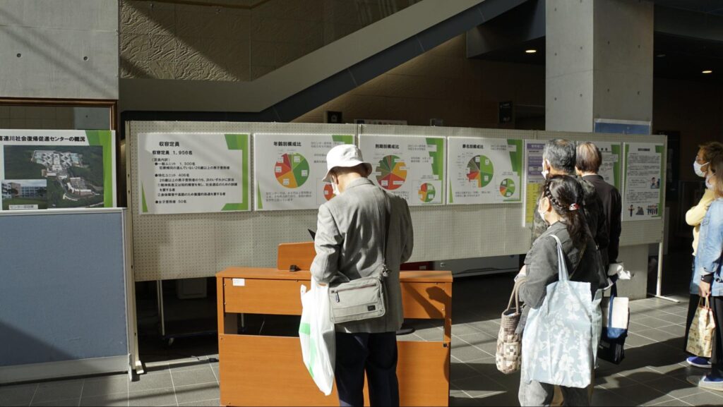 令和5年度きつれがわ矯正展(2023年11月23日開催)で展示された喜連川社会復帰促進センターで取り組まれている矯正に関する内容やデータを掲載する広報パネルを見る来場者