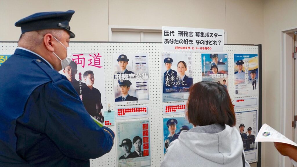 令和5年度きつれがわ矯正展(2023年11月23日開催)で展示された栃木県さくら市の歴代の刑務官募集ポスターを見る来場者