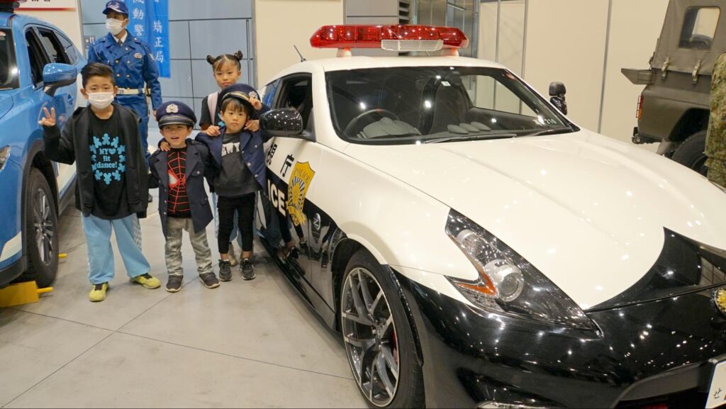 全国矯正展（2023年12月9、10日開催）に展示されていた警視庁のパトカーと記念撮影をする子どもたち
