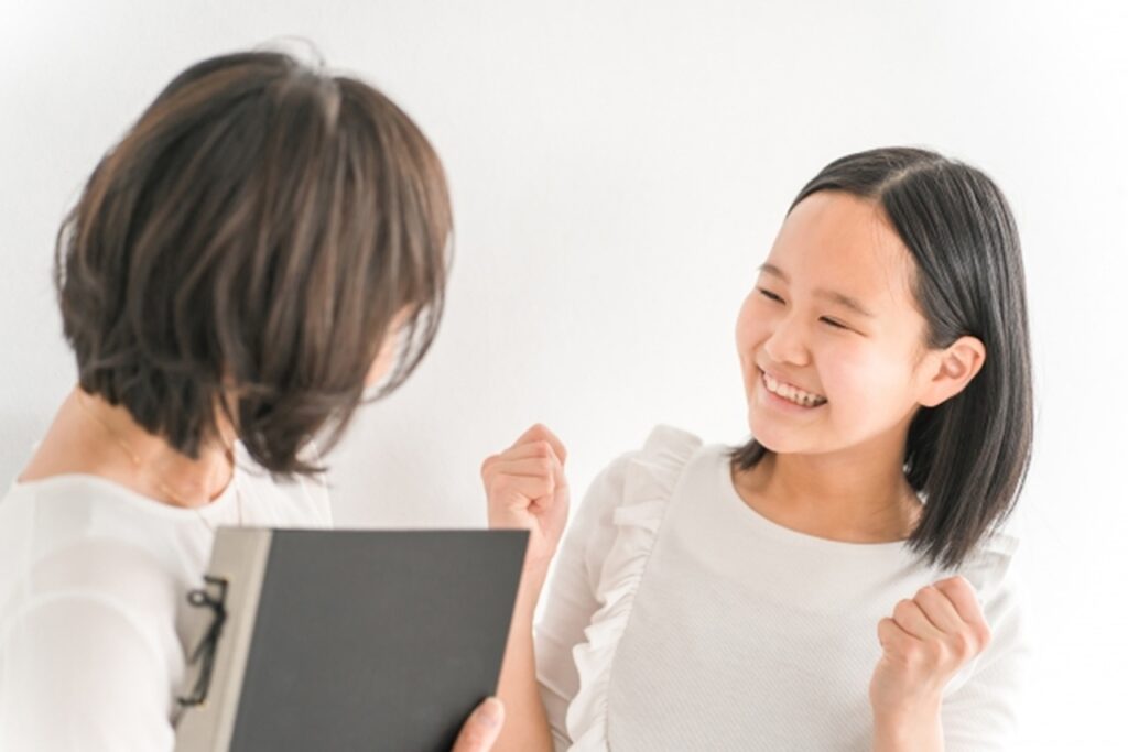 教師の個別指導を受けて喜ぶ女子生徒