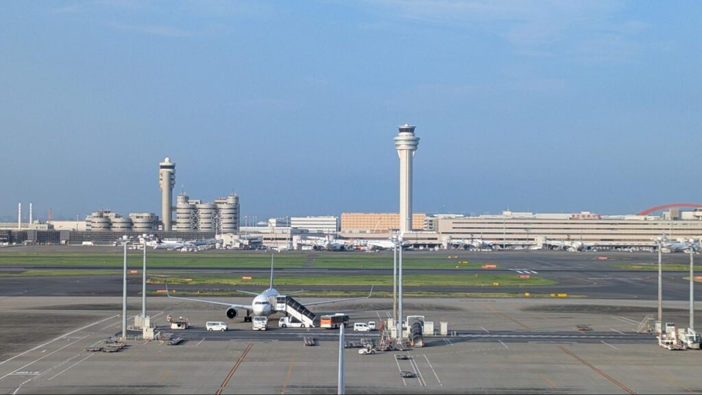 羽田空港の展望デッキから見た滑走路と駐機中の航空機。管制塔や第1・第2ターミナルビルが背景に広がる。