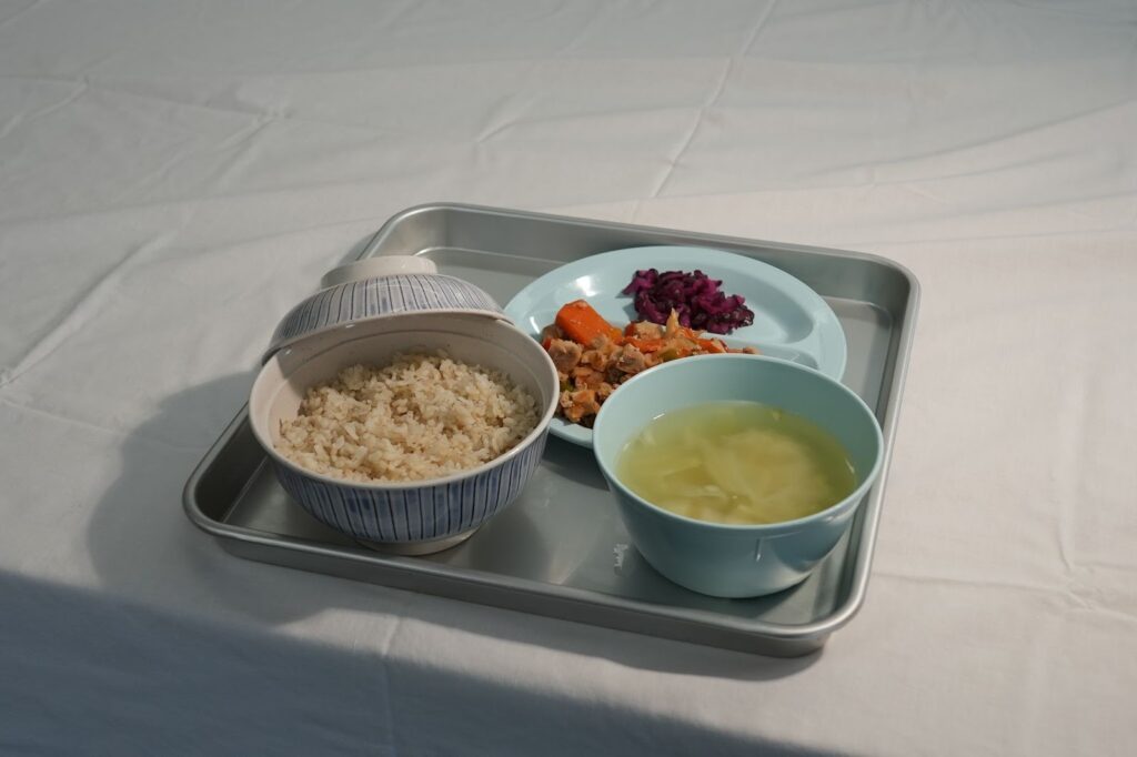 トレイに盛られた麦飯、スープ、煮物、副菜が載った再現食のセット