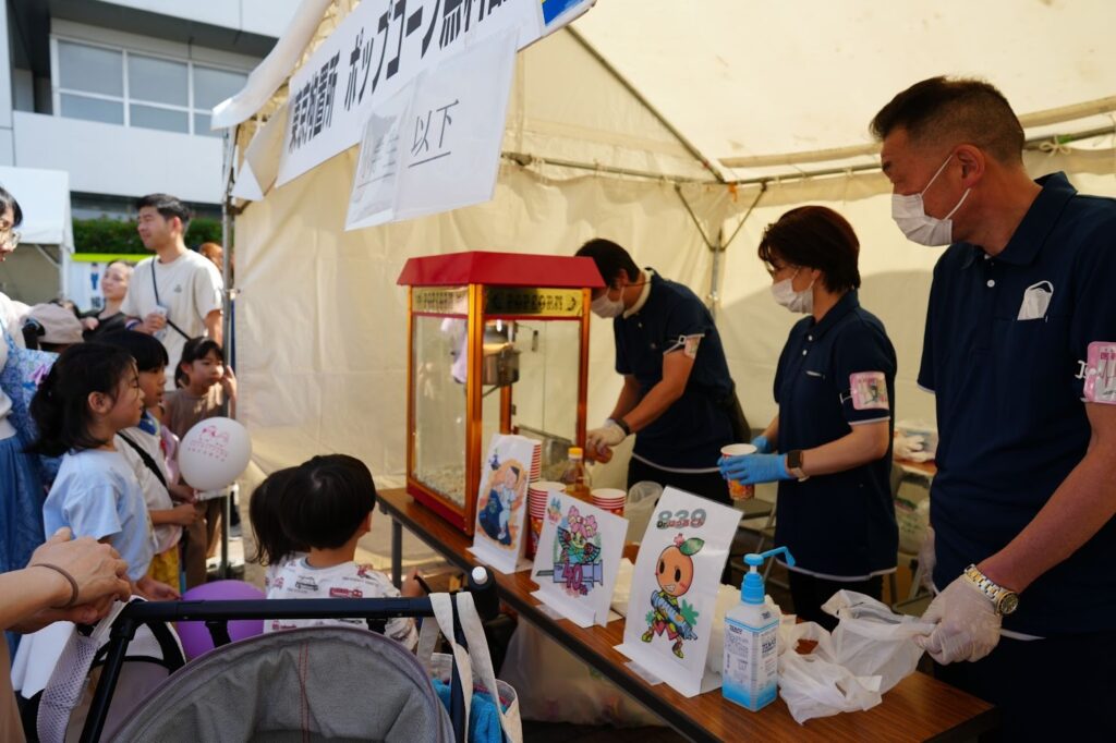 こどもたちが列を作り、東京拘置所職員がポップコーンを配布しているブースの様子。