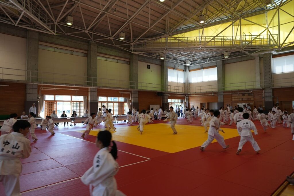 広い柔道場で、子どもたちが動きながら柔道の指導を受けている様子