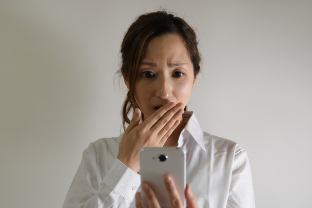 スマートフォンを見て驚く女性