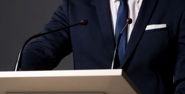 公聴会で釈明する男性