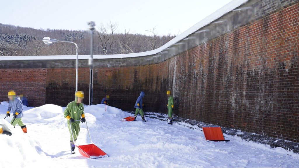 塀のそばの雪かきをする網走刑務所の受刑者