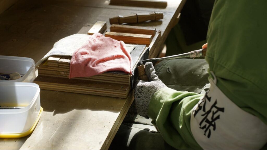 「ニポポ人形」を削る受刑者の手